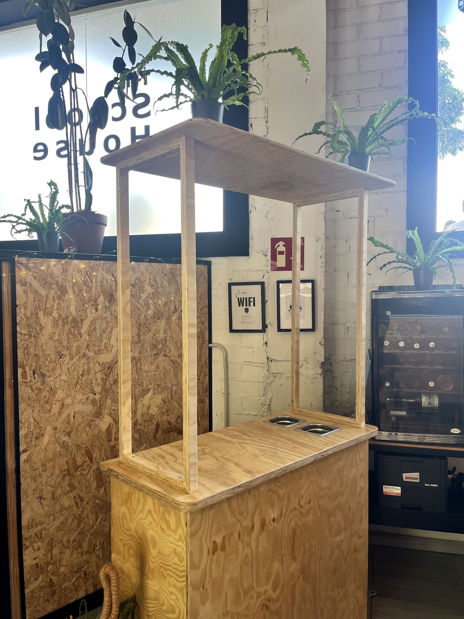 Plywood pop-up bar with an overhead frame and containers set into the counter