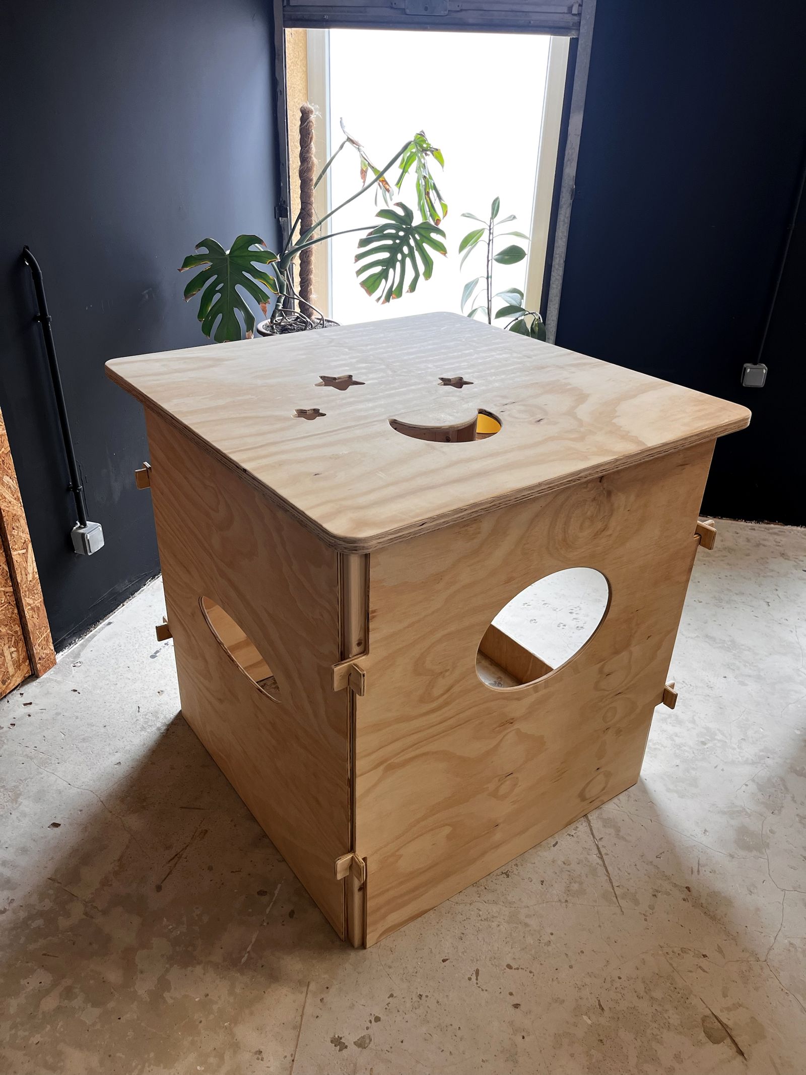 Plywood playhouse with stars and a moon cut into the roof