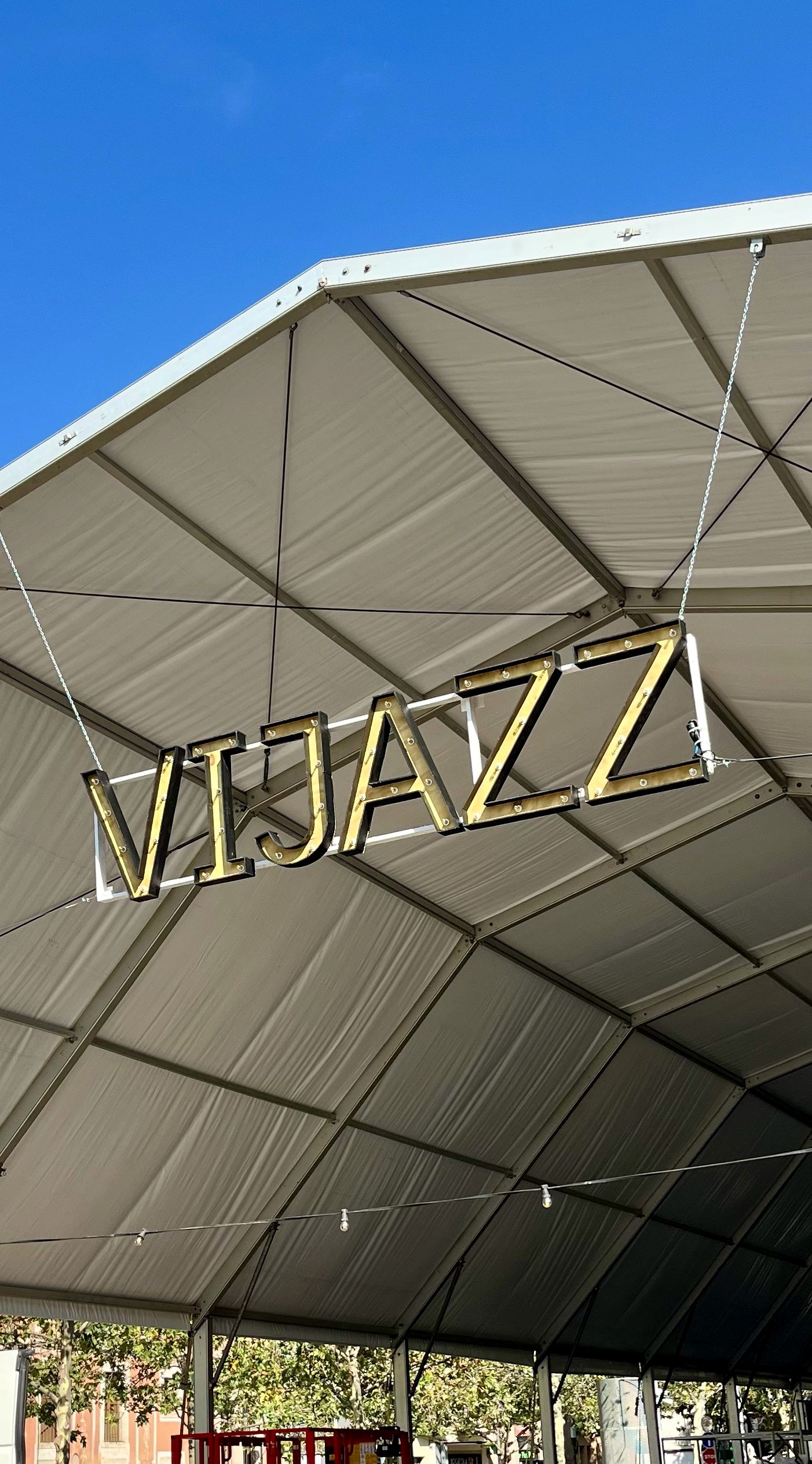 Gold marquee letters with bulbs spelling VIJAZZ, hanging under a tent